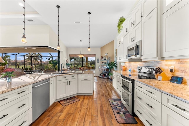 kitchen featuring sink, white cabinets, stainless steel appliances, and decorative light fixtures