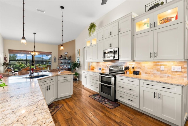 kitchen with white cabinets, sink, appliances with stainless steel finishes, tasteful backsplash, and decorative light fixtures