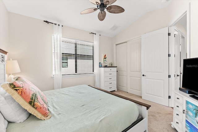 bedroom featuring ceiling fan, a closet, light carpet, and vaulted ceiling