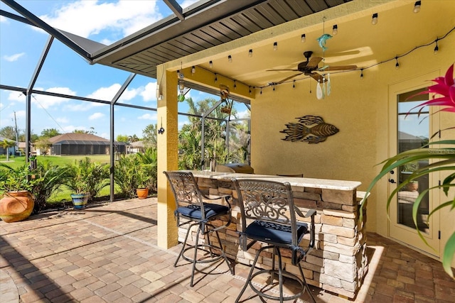 view of patio / terrace with glass enclosure, ceiling fan, and exterior bar