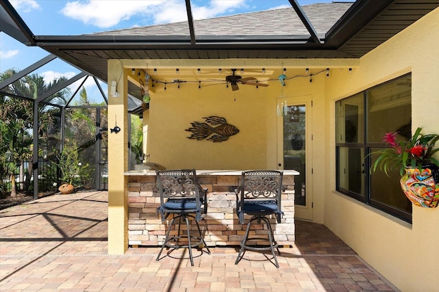 view of patio with glass enclosure, ceiling fan, and a bar