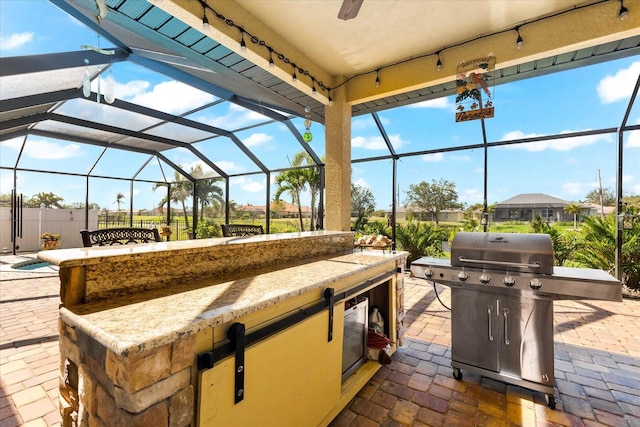 view of patio featuring glass enclosure and area for grilling