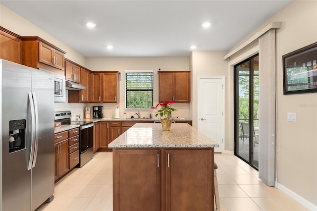 kitchen featuring a center island, sink, tasteful backsplash, light stone counters, and stainless steel appliances