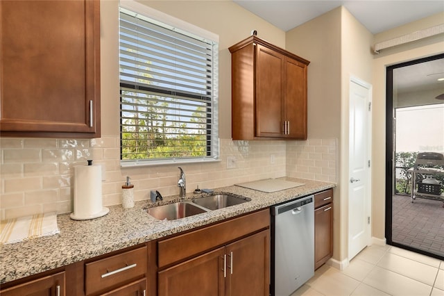 kitchen with light stone countertops, dishwasher, sink, decorative backsplash, and light tile patterned flooring