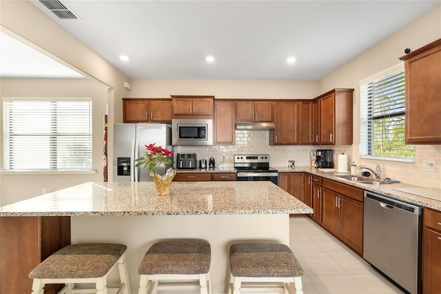 kitchen featuring a kitchen breakfast bar, a kitchen island, sink, and appliances with stainless steel finishes