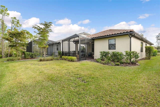 back of property featuring glass enclosure and a lawn