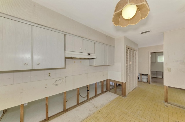 kitchen with tasteful backsplash and white cabinetry