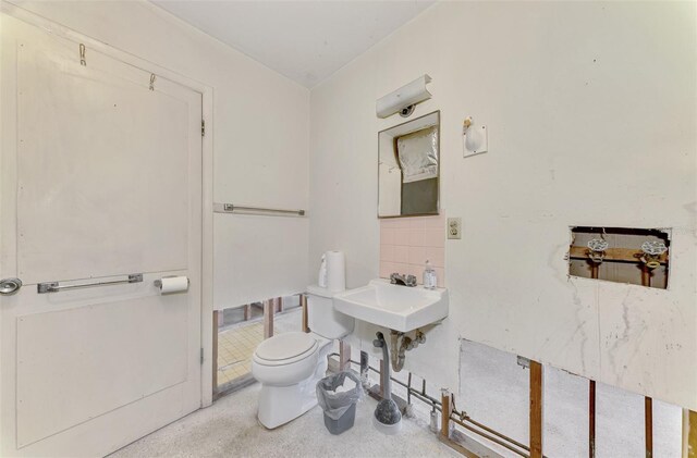 bathroom with backsplash, toilet, and sink