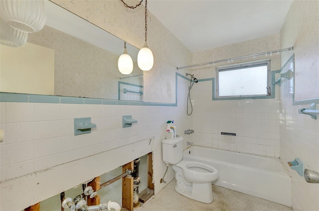 bathroom with tiled shower / bath, tile walls, and toilet