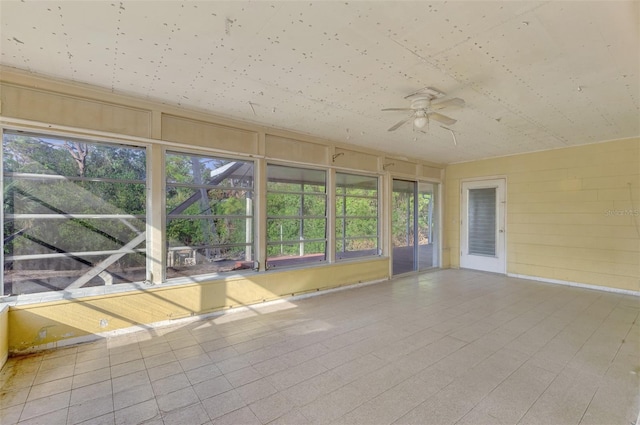 unfurnished sunroom featuring ceiling fan and plenty of natural light