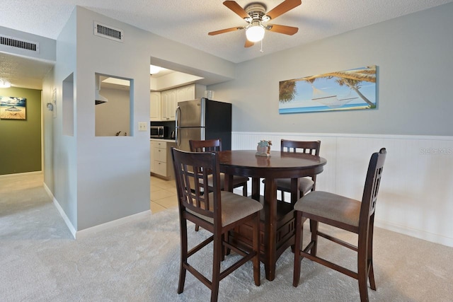 carpeted dining space with ceiling fan and a textured ceiling