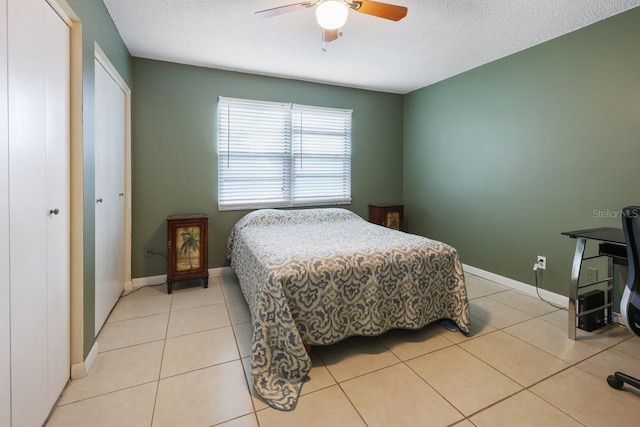 bedroom featuring ceiling fan, a textured ceiling, a closet, and light tile patterned flooring