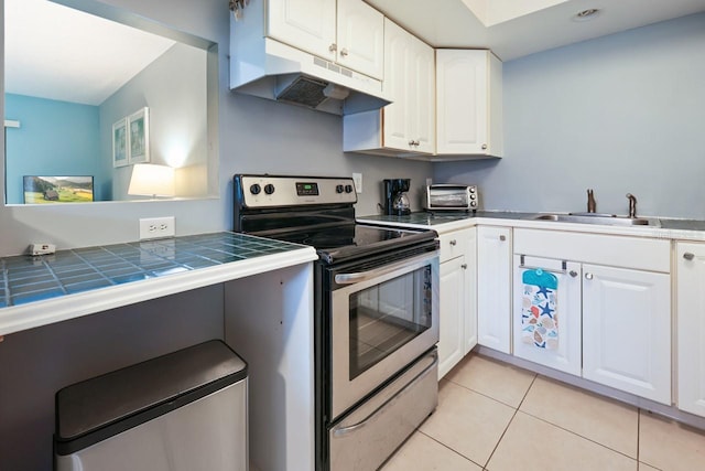 kitchen featuring white cabinets, sink, stainless steel electric range oven, tile countertops, and light tile patterned floors