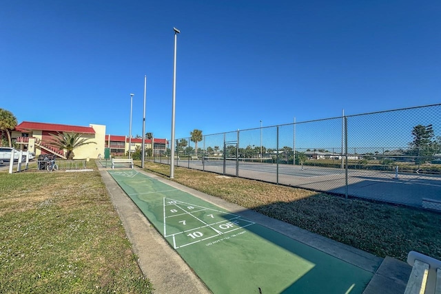 view of property's community featuring tennis court and a yard