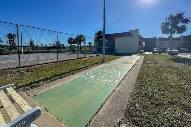 view of community with tennis court and a lawn