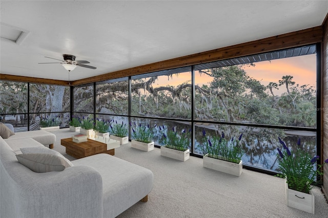 sunroom / solarium featuring ceiling fan and a water view