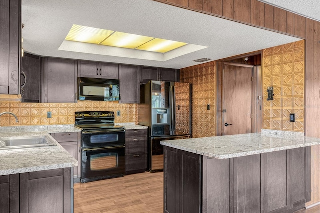 kitchen with dark brown cabinetry, sink, a textured ceiling, black appliances, and light wood-type flooring