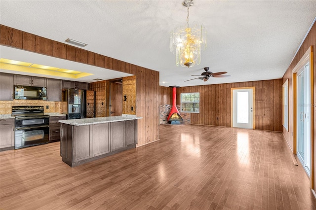 kitchen featuring black appliances, a textured ceiling, and wooden walls