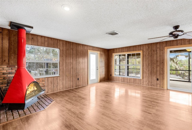 interior space featuring a textured ceiling, a wood stove, and ceiling fan