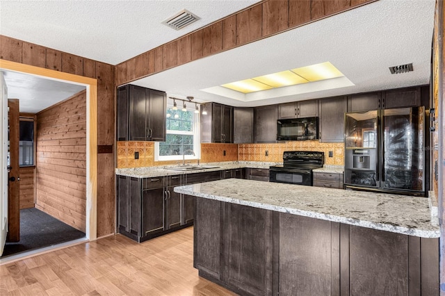 kitchen with black appliances, dark brown cabinets, sink, and wooden walls