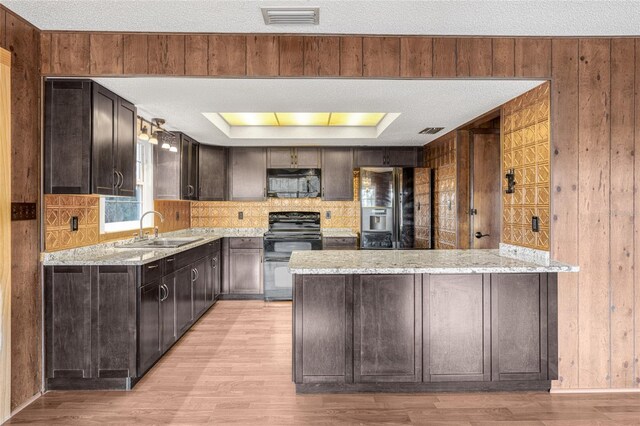 kitchen with wood walls, sink, and black appliances