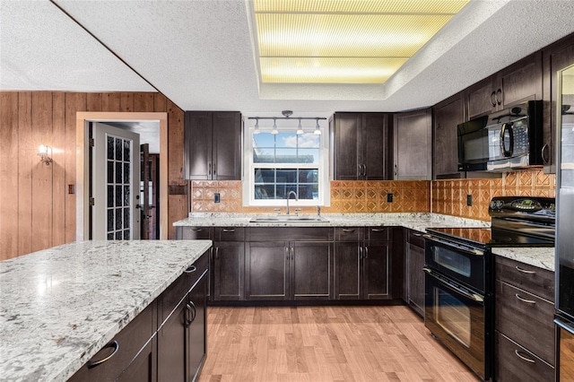 kitchen featuring light stone countertops, sink, a textured ceiling, a tray ceiling, and black appliances