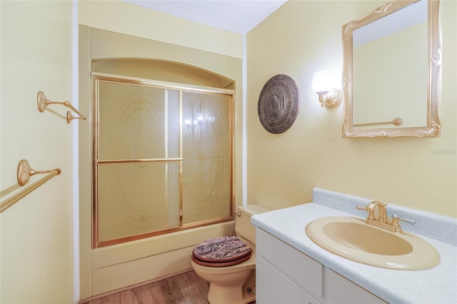 full bathroom with hardwood / wood-style flooring, vanity, toilet, and shower / bath combination with glass door