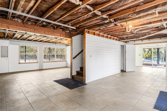 basement with light tile patterned floors, electric panel, and plenty of natural light