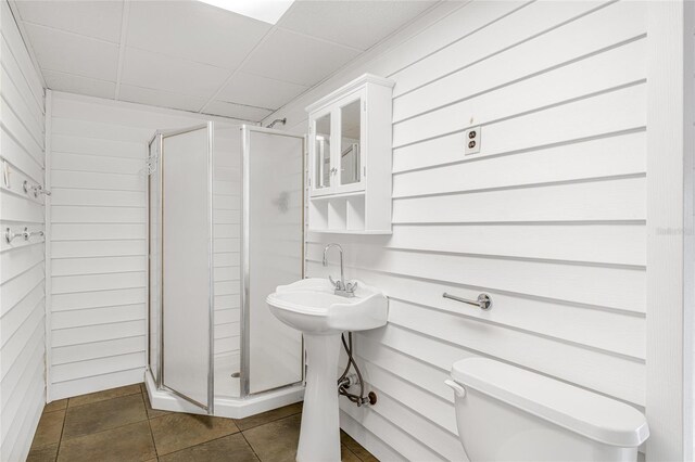 bathroom featuring toilet, wood walls, and an enclosed shower