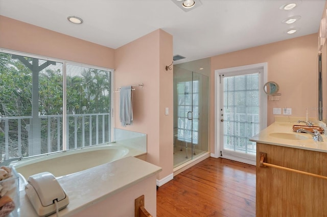 bathroom featuring hardwood / wood-style flooring, vanity, and plus walk in shower