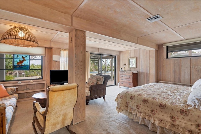 carpeted bedroom featuring multiple windows, access to exterior, and wooden walls