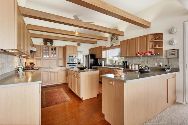 kitchen with a kitchen island, appliances with stainless steel finishes, backsplash, kitchen peninsula, and beam ceiling