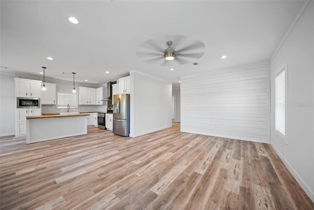 unfurnished living room featuring crown molding, ceiling fan, and a healthy amount of sunlight