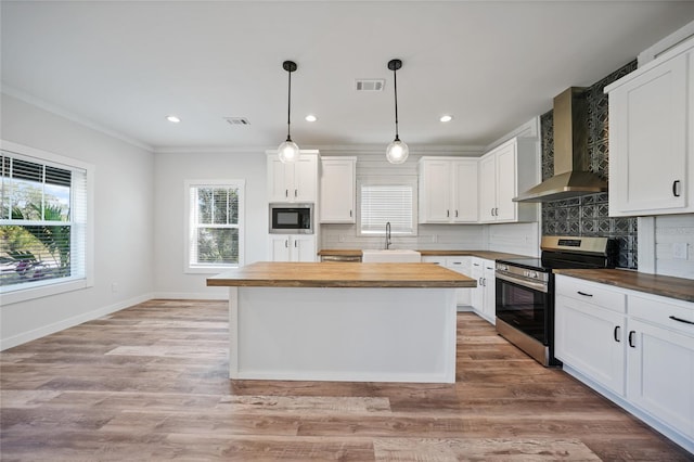 kitchen with wooden counters, built in microwave, wall chimney range hood, electric range, and white cabinets