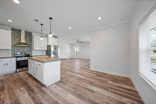 kitchen with white cabinets, appliances with stainless steel finishes, and wall chimney range hood