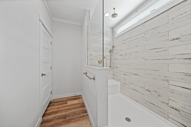 bathroom with hardwood / wood-style floors, crown molding, and tiled shower