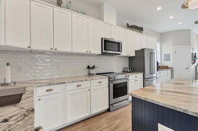 kitchen featuring light stone countertops, backsplash, stainless steel appliances, light hardwood / wood-style flooring, and white cabinets