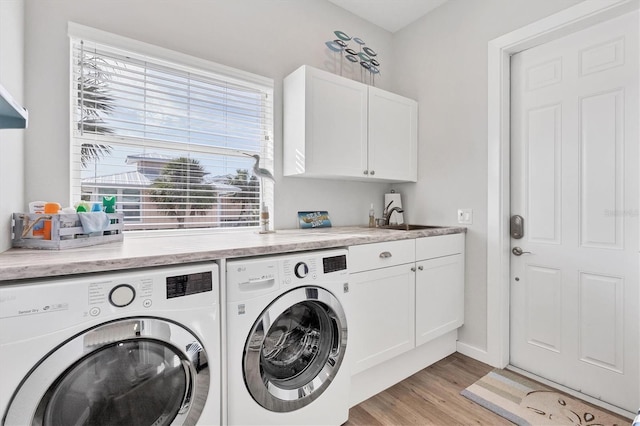 laundry room with light hardwood / wood-style floors, sink, cabinets, and independent washer and dryer