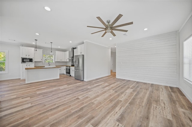 unfurnished living room featuring ceiling fan, light hardwood / wood-style floors, and crown molding