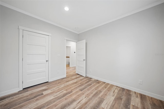 unfurnished bedroom featuring light wood-type flooring, crown molding, and a closet