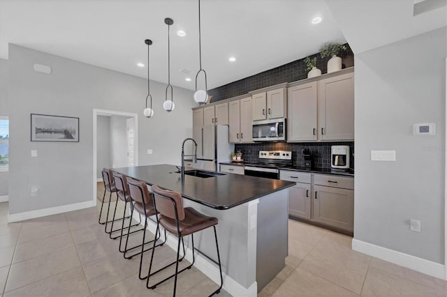 kitchen with pendant lighting, a kitchen island with sink, sink, light tile patterned floors, and stainless steel appliances