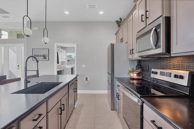 kitchen with hanging light fixtures, sink, light tile patterned floors, independent washer and dryer, and appliances with stainless steel finishes