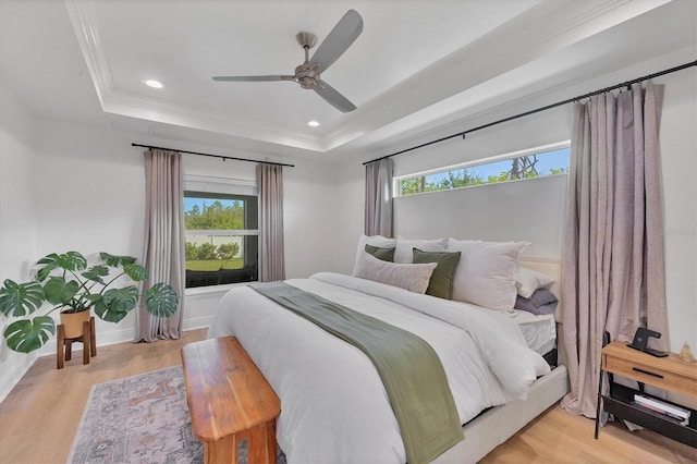 bedroom with a raised ceiling, ceiling fan, and light hardwood / wood-style flooring