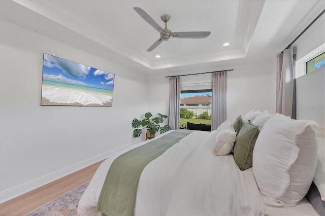 bedroom featuring hardwood / wood-style floors, a tray ceiling, ceiling fan, and ornamental molding