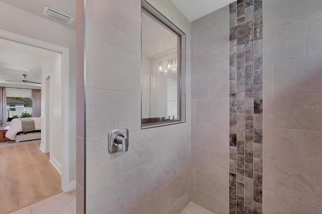 bathroom with hardwood / wood-style flooring, ceiling fan, and tiled shower