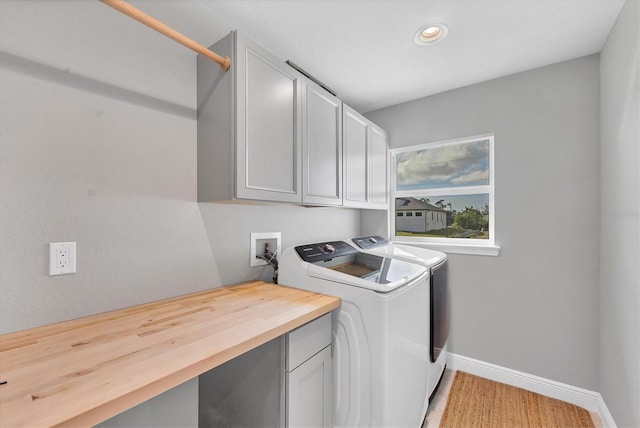 clothes washing area featuring cabinets, wood-type flooring, and washing machine and dryer