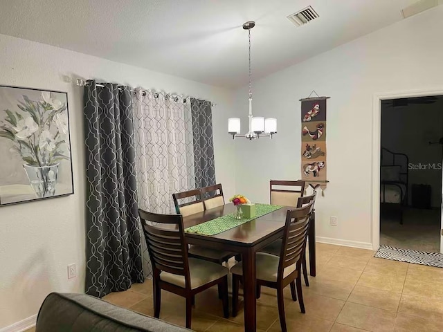 tiled dining space featuring vaulted ceiling and a chandelier