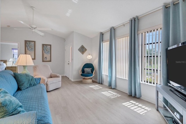 living area with a ceiling fan, vaulted ceiling, wood finished floors, and baseboards