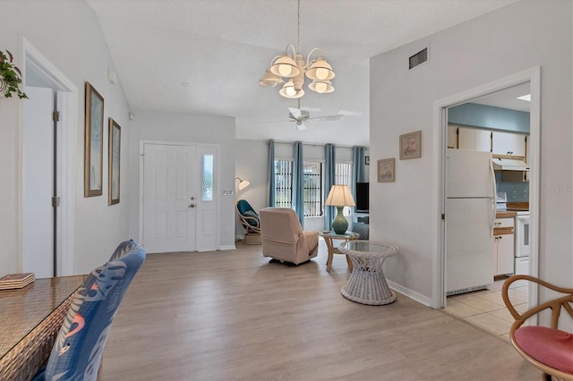 foyer with ceiling fan with notable chandelier, baseboards, visible vents, and light wood-type flooring