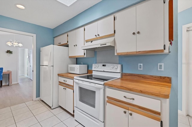 kitchen featuring under cabinet range hood, an inviting chandelier, light tile patterned flooring, white appliances, and white cabinetry